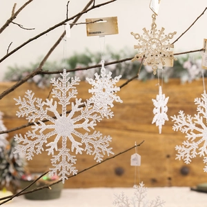 Glittering snowflake Christmas tree ornaments in gold and pink hanging on rustic branches