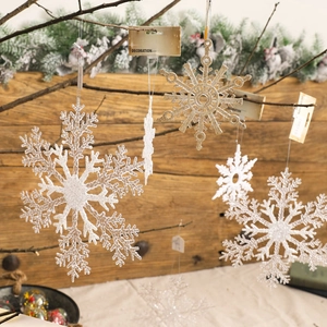 Sparkling white and gold Christmas snowflake ornaments set hanging on winter branches