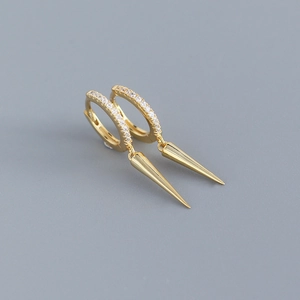Detail of gold hoop earring with pavé zircon stones and long hanging metal spike pendant