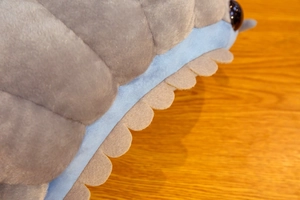 Detail of plush caterpillar toy with soft grey wavy trim and blue fabric segments