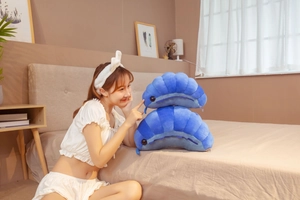 Detail showing two blue shell-shaped plush pillows made of soft velvet on a cozy bed