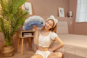 Close-up of a soft grey and blue caterpillar plush toy held by a girl in a bedroom