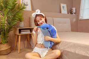 Detail view of a soft blue pill bug plush toy being held in a cozy bedroom setting