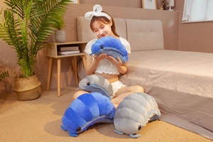 Plush isopod toys in blue and grey being held by a model in a cozy bedroom setting