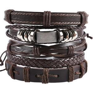 Multilayer dark brown braided leather bracelet set with vintage metal charms on white background