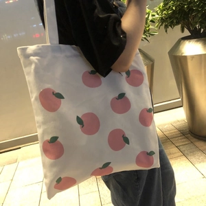 Detailed close-up of a white canvas tote bag featuring cute pink peach patterns