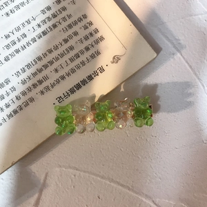 Detail of cute bear hair clip with green resin charms on a vintage book page