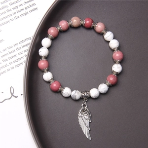 Detailed shot of pink and white marble bead bracelet with a silver angel wing charm