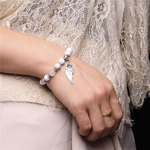 Detail of beaded bracelet with marble white stones, pink beads and silver wing pendant