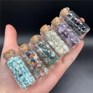 Detailed view of hand-held small glass bottles filled with various healing crystal stones