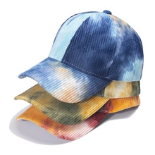 Detailed stack of tie-dye corduroy baseball caps in blue, yellow, and red color patterns