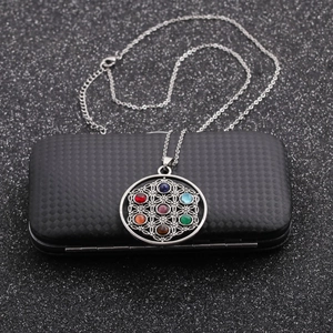 Detail of Flower of Life pendant with seven colorful gemstones on black textured box