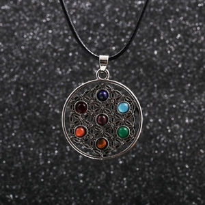 Macro view of Flower of Life pendant with seven colorful gemstones on black cord