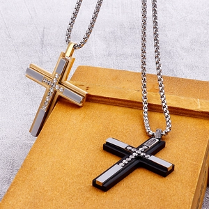 Close-up of gold and black cross necklaces with silver inlay on a rustic wood box