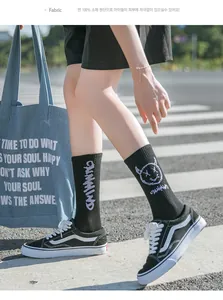 Gros plan de chaussettes en coton noir avec motif de sourire démoniaque et lettrage blanc