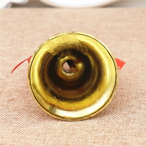 Close-up of a 5cm golden Christmas bell showing inner details and a red ribbon