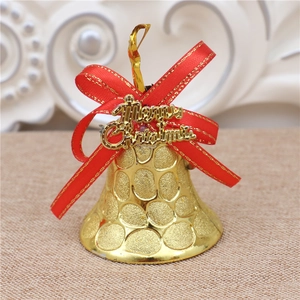 Close-up of golden Christmas bell with red ribbon bow and Merry Christmas plaque