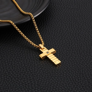 Macro shot of gold cross pendant with black gemstone and box chain on leather background