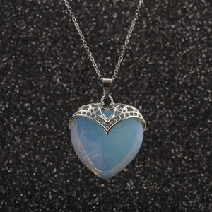 Collier avec pendentif cœur opale bleu clair et chaîne en argent sur fond noir scintillant