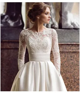 Detailed view of white lace long sleeves and high waist pleated satin bridal gown