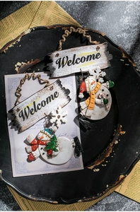 Close-up of Snowman Welcome ornaments with rustic wood signs and vintage newspaper decor
