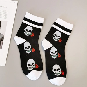 Détail de chaussettes gothiques en coton avec motif crâne et rose sur fond noir