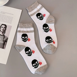 Détail de chaussettes blanches avec motifs tête de mort punk et roses rouges et talons gris
