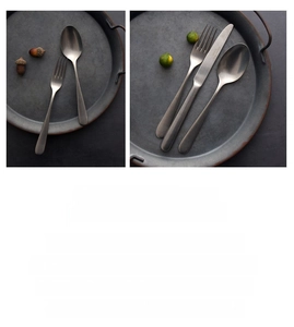 Close-up of retro matte dark grey stainless steel cutlery set on rustic plates