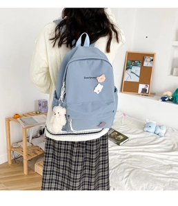 Close-up of light blue aesthetic backpack featuring cute bear plush and cartoon badges