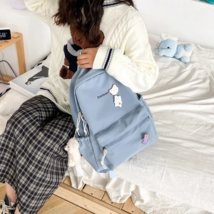 Close-up of blue nylon backpack featuring Duociyuan logo and cute 3D bear ornaments