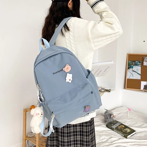 Blue minimalist backpack for students with cute bear badges and plush bear accessory