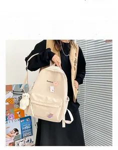 Detail view of cream canvas backpack with cute bear embroidery and plush charm pendant