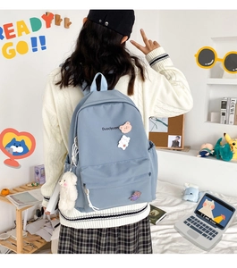 Detail of light blue school backpack with cute bear pendant and badges on back