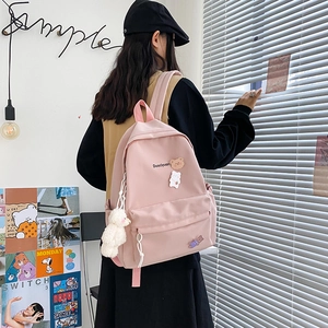 Pink canvas backpack with cute bear embroidery and plush pendant shown on a model