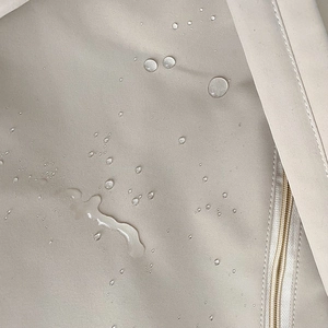 Detalle de tela beige impermeable con gotas de agua y cremallera a juego de la mochila
