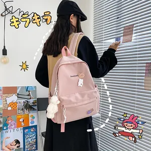Detailed side view of a pink canvas school bag featuring cute bear charms and logo print