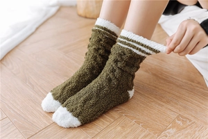 Detail of green coral fleece sleep socks with white stripes on a wooden floor