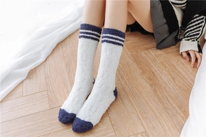 Detail showing plush texture of striped coral fleece sleep socks for women on wood floor