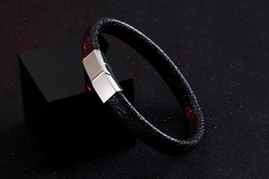 Detail of black embossed leather bracelet with silver mirror finish metal clasp on stand