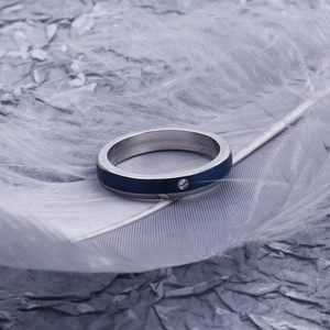 Detailed macro view of a slim stainless steel ring with blue inlay and small diamond
