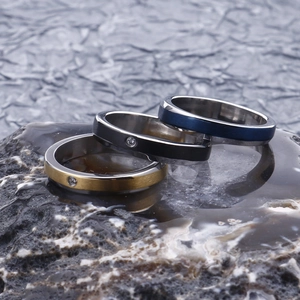 Detailed macro view of gold, blue, and black stainless steel rings with small inlaid diamonds