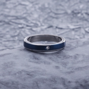 Close-up of silver steel ring with blue brushed inlay and single diamond on stone
