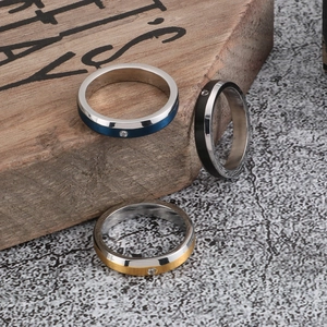 Polished stainless steel rings in blue, gold and black with zircon stones on wood stand