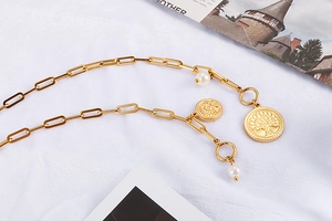 Détail d'un collier en titane doré orné de perles et d'un pendentif arbre de vie