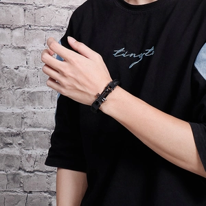 Men's black woven leather bracelet with stainless steel cross clasp on a male wrist