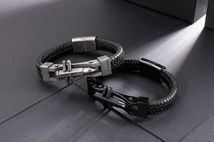 Detail of men's woven black leather bracelets with silver and black bullet-shaped metal clasps