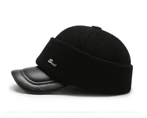 Detailansicht der schwarzen Strickmütze mit Lederschirm und Sport-Logo an der Seite