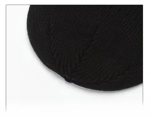 Close-up of the precise stitching and fine rib-knit texture on top of this black winter beanie