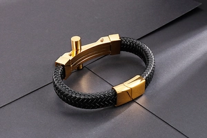 Detail of black woven leather strap and golden magnetic clasp on men's cross bracelet