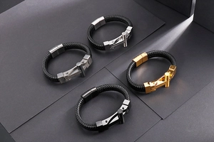 Detail of men's braided leather bracelets with cross clasp in silver, gold, and gunmetal